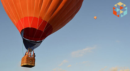 Lecący pomarańczowy balon na tle niebieskiego nieba