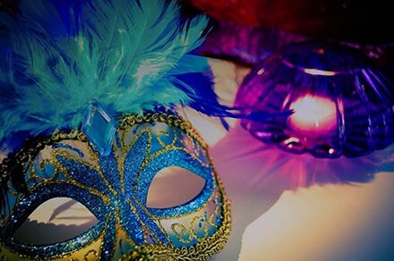 Maski tetralne zdobione kolorowymi pióramia leżące na stole